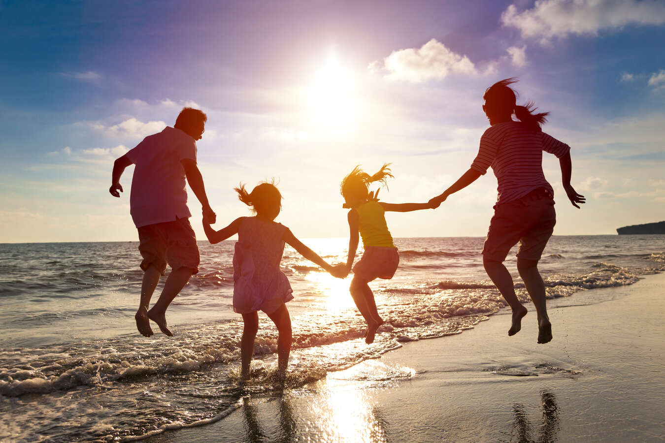Family walking along a bright ocean shoreline